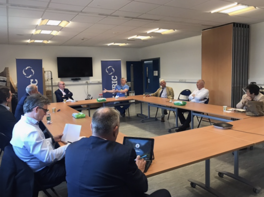 Image from Trevor Ringland visit, with members of staff around a table.